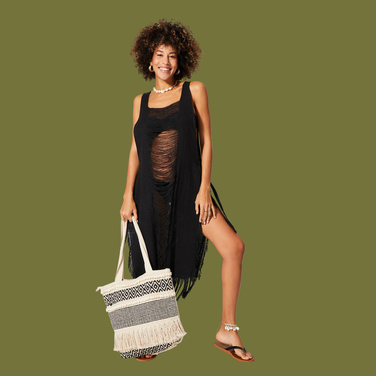 Woman in a black dress holding a beach bag on a white background